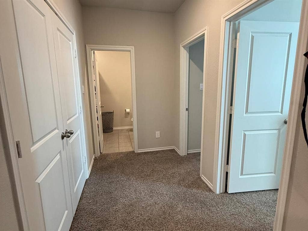 Neutral-toned interior featuring textured carpeting, double-panel interior doors, and tiled flooring