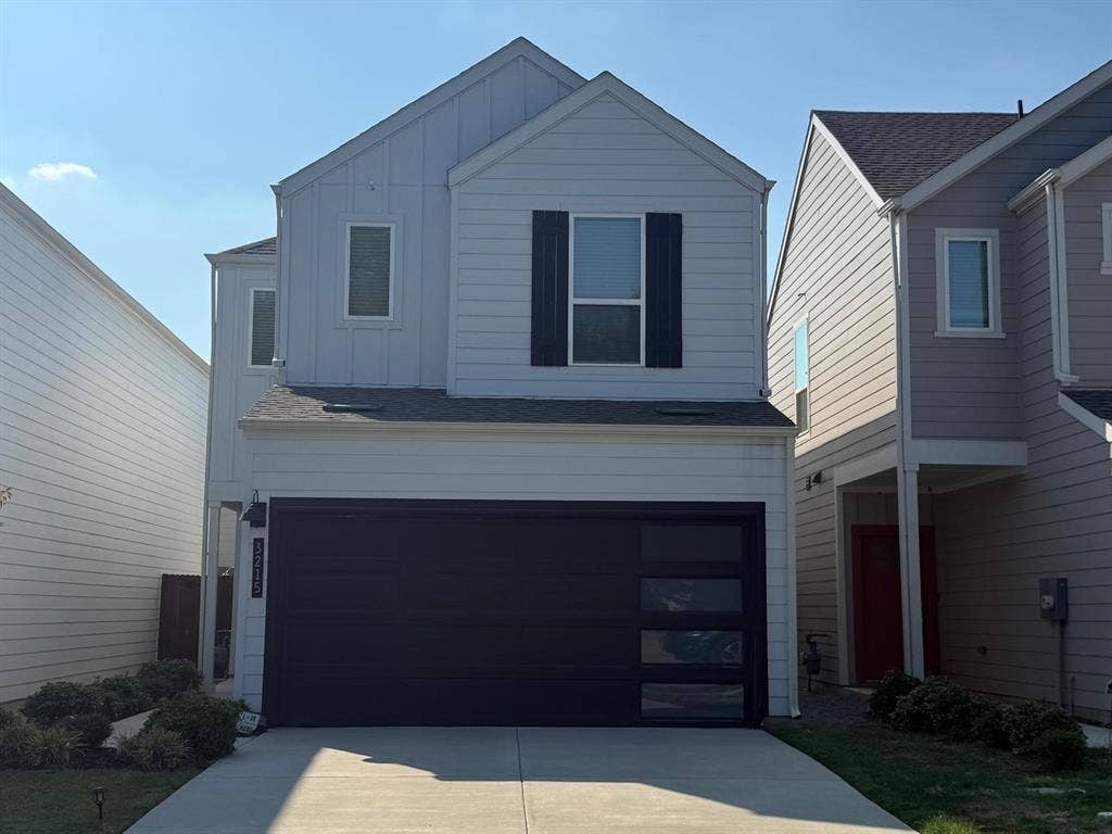 Two-story exterior featuring white horizontal siding, vertical board-and-batten accents, black window shutters, and a modern garage door with integrated glass panels