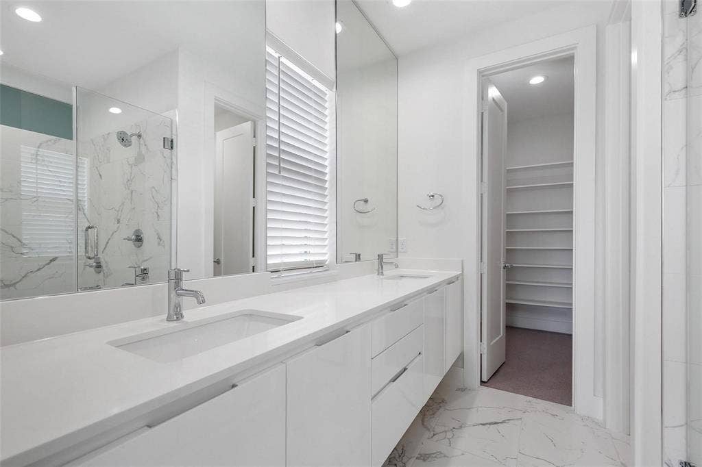 4904 Lexington Court, Dallas, TX 75206 Floating white vanity with dual rectangular sinks, quartz countertops, floor-to-ceiling mirrors, large-format stone-finish tile flooring, and a walk-in storage area with custom shelving