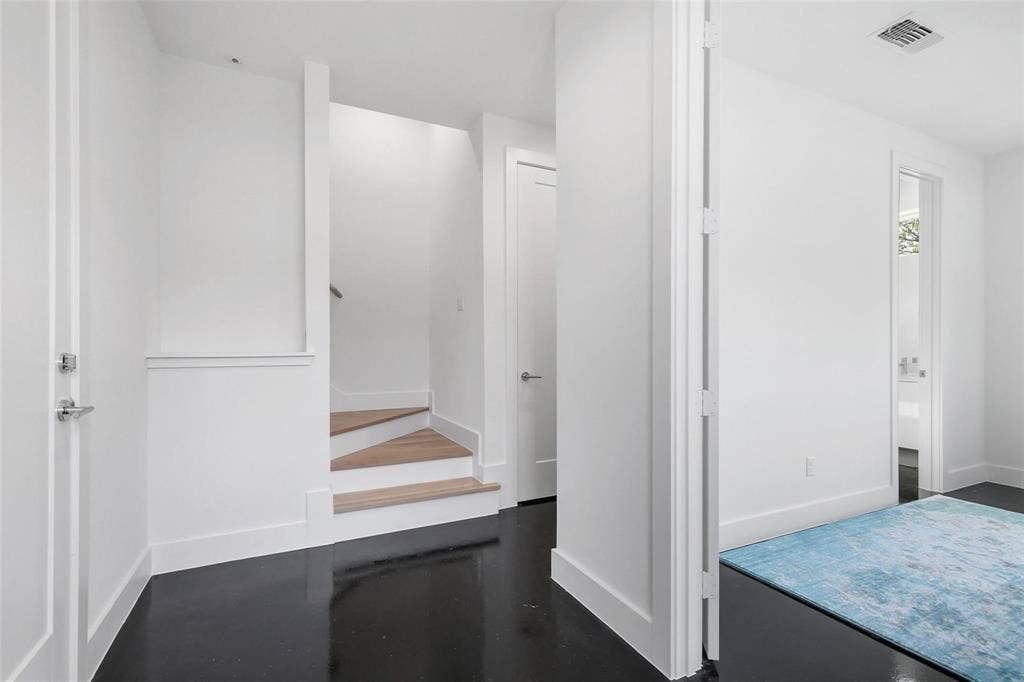 4904 Lexington Court, Dallas, TX 75206 Minimalist interior featuring dark polished flooring, wood-finish stair treads, crisp white walls, and interior doors with satin-nickel lever hardware