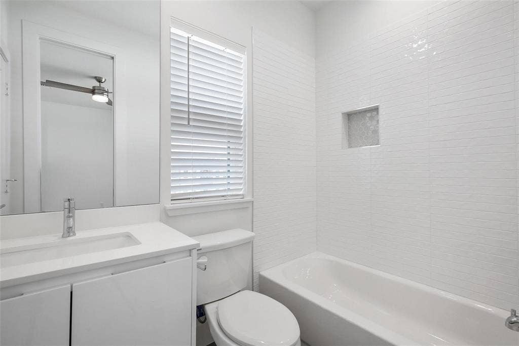 4904 Lexington Court, Dallas, TX 75206 Bathroom featuring a white vanity with an integrated rectangular sink, a large wall-mounted mirror, a tub-shower combination with horizontal tile surround, and a recessed wall niche