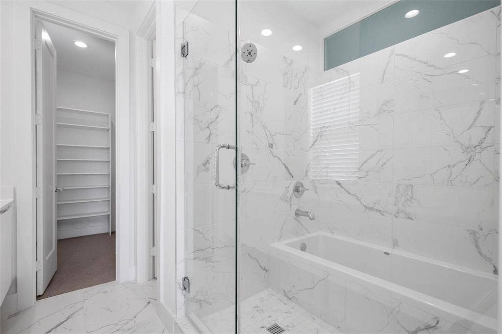 4904 Lexington Court, Dallas, TX 75206 Bathroom featuring a walk-in shower with a frameless glass door, a deep soaking tub, and floor-to-ceiling stone-finish tile surround