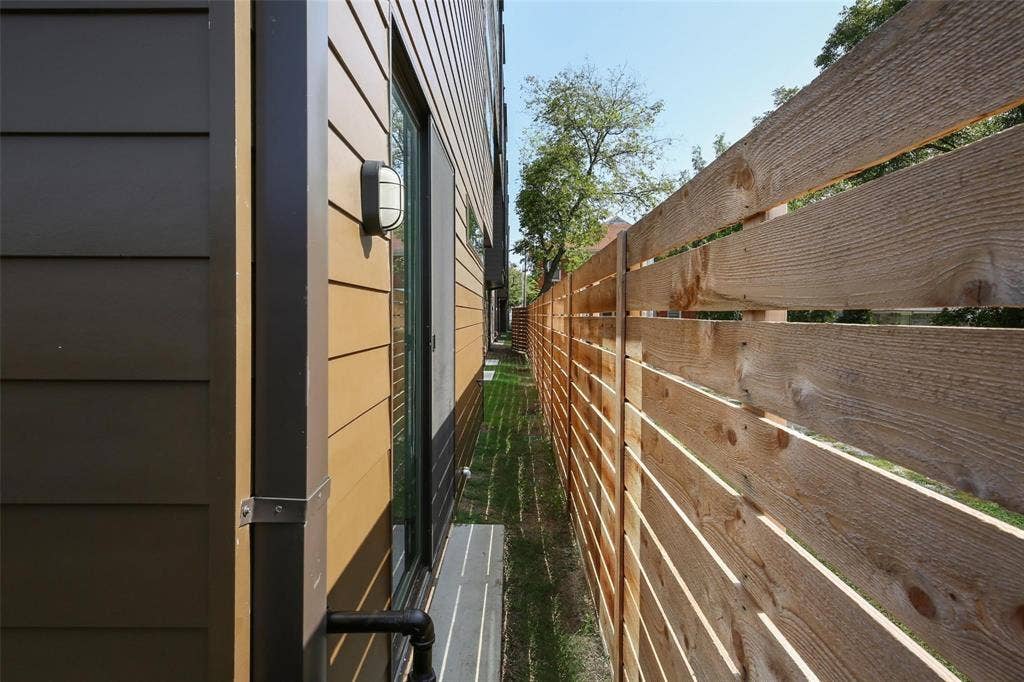 4904 Lexington Court, Dallas, TX 75206 Exterior side passage featuring horizontal lap siding, a metal downspout, wall-mounted bulkhead light fixture, and a horizontal wood-slat privacy fence