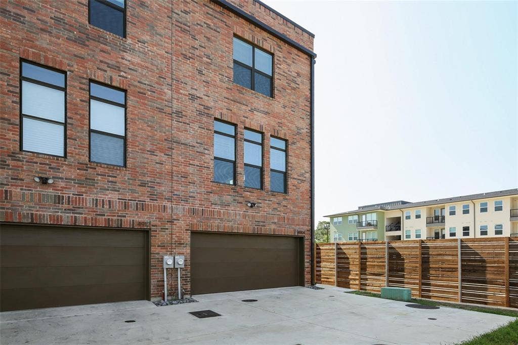 4904 Lexington Court, Dallas, TX 75206 Multi-level brick exterior featuring dual garages, horizontal wood-slat fencing, and black-framed windows