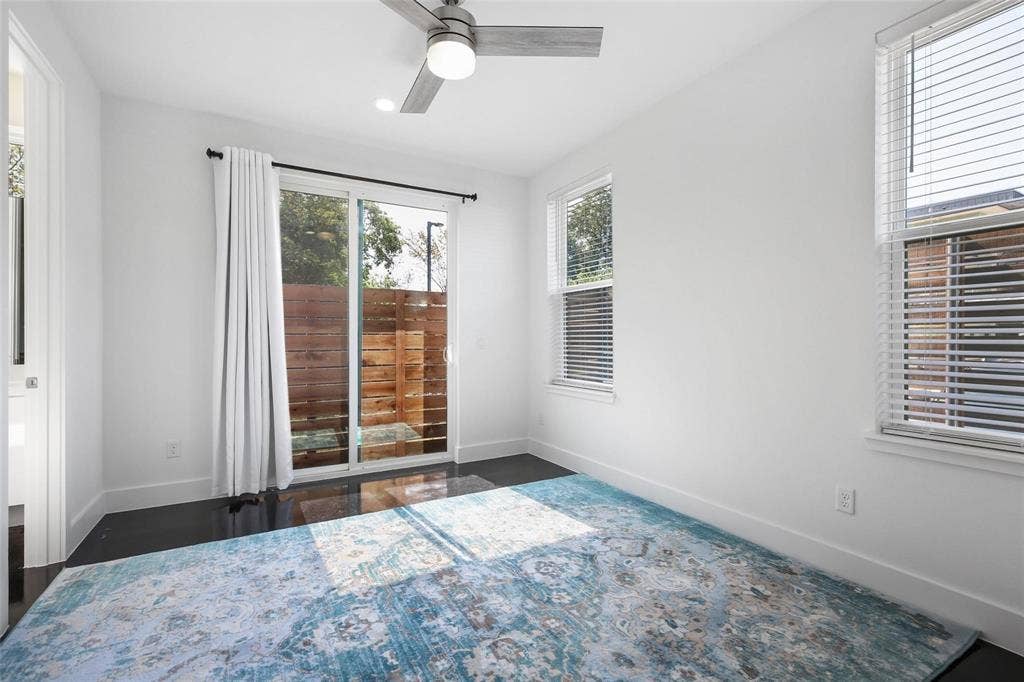 4904 Lexington Court, Dallas, TX 75206 Dark-toned wood-finish flooring, sliding glass door with external wood privacy fencing, ceiling fan with integrated lighting, and horizontal window blinds
