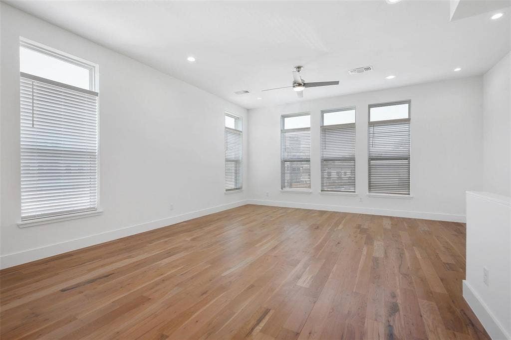 4904 Lexington Court, Dallas, TX 75206 Spacious room featuring wood-finish flooring, recessed lighting, a brushed-metal ceiling fan, and multiple windows with integrated blinds