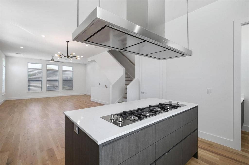 4904 Lexington Court, Dallas, TX 75206 Kitchen island featuring quartz countertops, dark cabinetry, and an integrated gas cooktop, complemented by a stainless steel ceiling-mounted range hood, wood-finish flooring, and recessed lighting