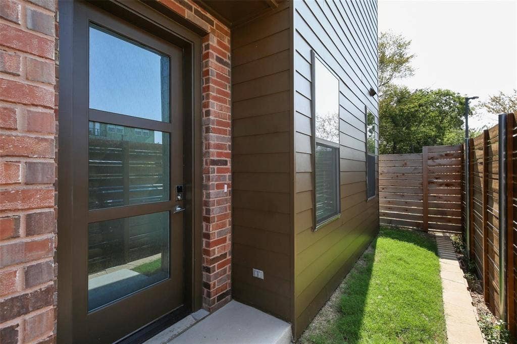 4904 Lexington Court, Dallas, TX 75206 Exterior entrance featuring a glass-panel door, mixed-material facade of brick and horizontal siding, concrete walkway, and private fenced yard