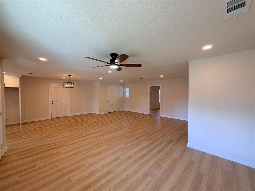 Open interior featuring wood-finish flooring, recessed lighting, a modern ceiling fan, and multi-light pendant fixture