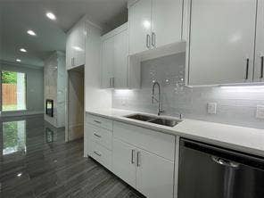 Kitchen featuring high-gloss white cabinetry, quartz countertops, a stainless steel undermount sink with a gooseneck faucet, light-toned subway tile backsplash, and polished stone-finish flooring