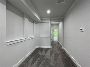 Neutral-toned interior hallway featuring recessed wall niches with millwork accents, grey carpeting, and recessed lighting
