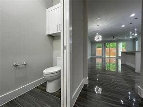 Powder room featuring a dual-flush toilet, wall-mounted cabinetry, dark wood-finish tile flooring, recessed lighting, and expansive sliding glass doors