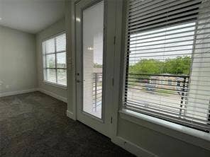 Interior space featuring wall-to-wall carpeting, multiple windows with horizontal blinds, and a glass-paneled exterior door