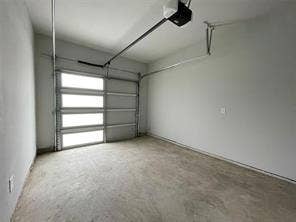 Attached garage featuring concrete flooring, smooth-finished walls, and an overhead sectional door with integrated glass panels