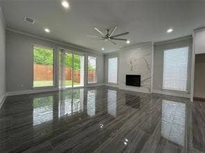 Living area featuring large-format polished tile flooring, floor-to-ceiling stone-surround fireplace, recessed lighting, brushed metal ceiling fan, and multi-panel sliding glass doors