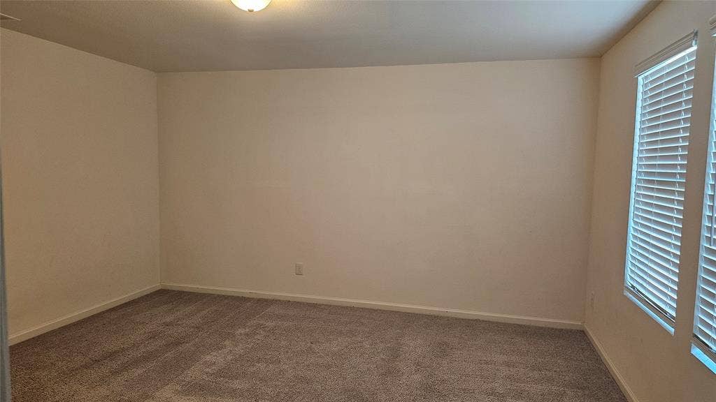 Neutral-toned carpeted flooring, light-colored walls, and two windows with horizontal blinds