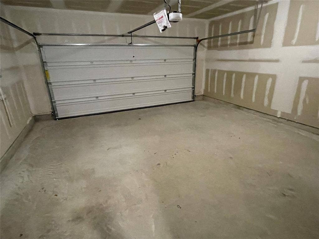 Garage featuring a sectional overhead door, concrete flooring, and unfinished drywall walls