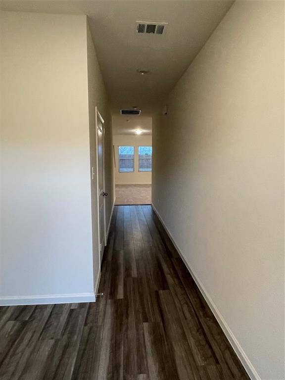 Hallway featuring neutral wall tones and dark wood-finish flooring