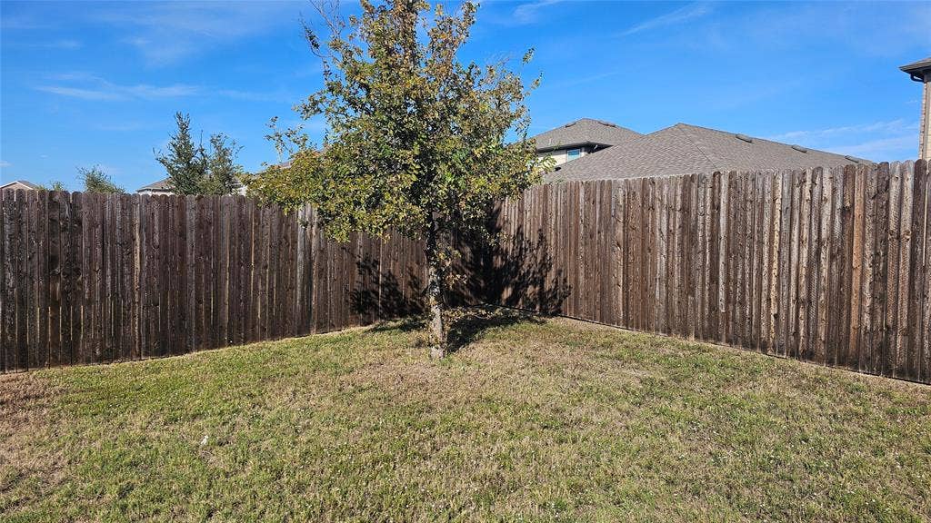 Backyard featuring a vertical wood privacy fence and mature tree