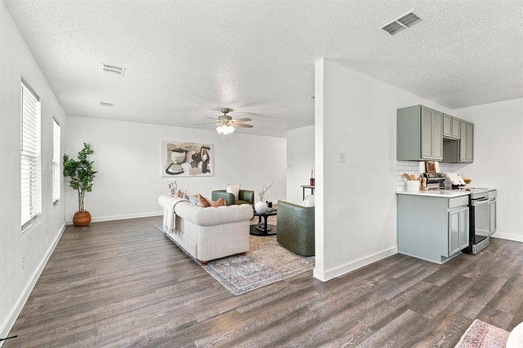 Open-concept living space featuring wood-finish flooring, recessed lighting, ceiling fan, and kitchen cabinetry with a subway tile backsplash