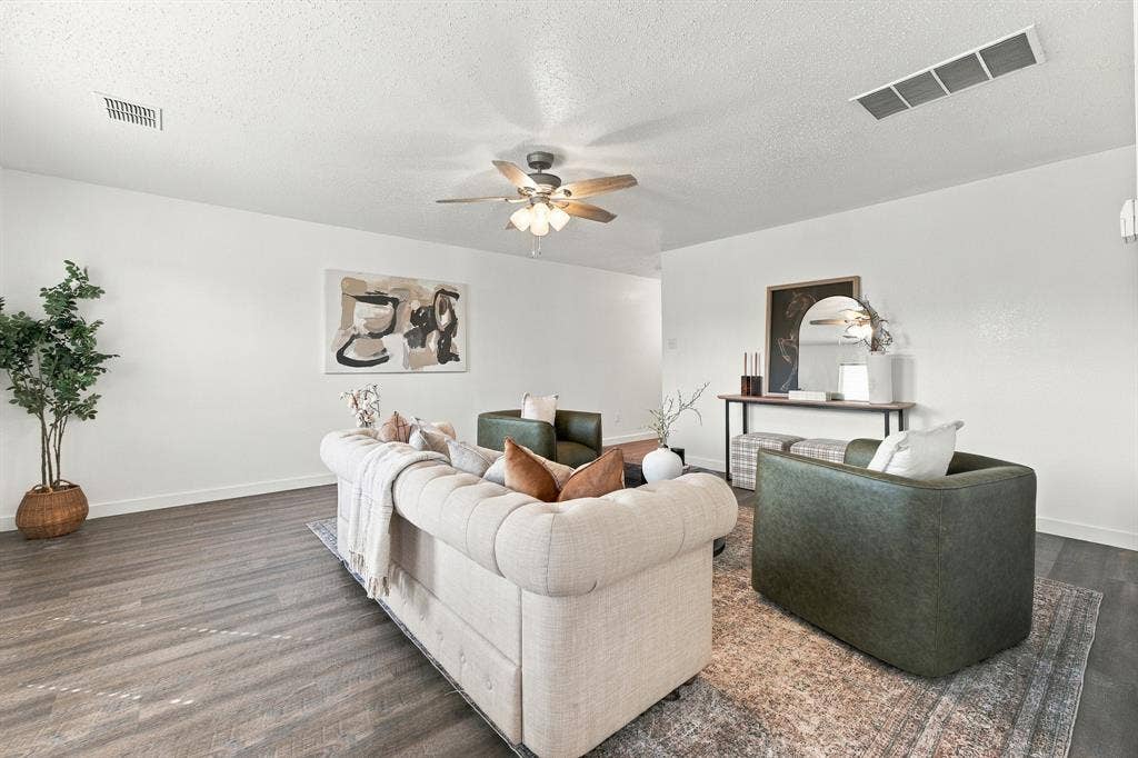 Neutral interior space featuring wood-finish flooring and a central ceiling fan with integrated lighting