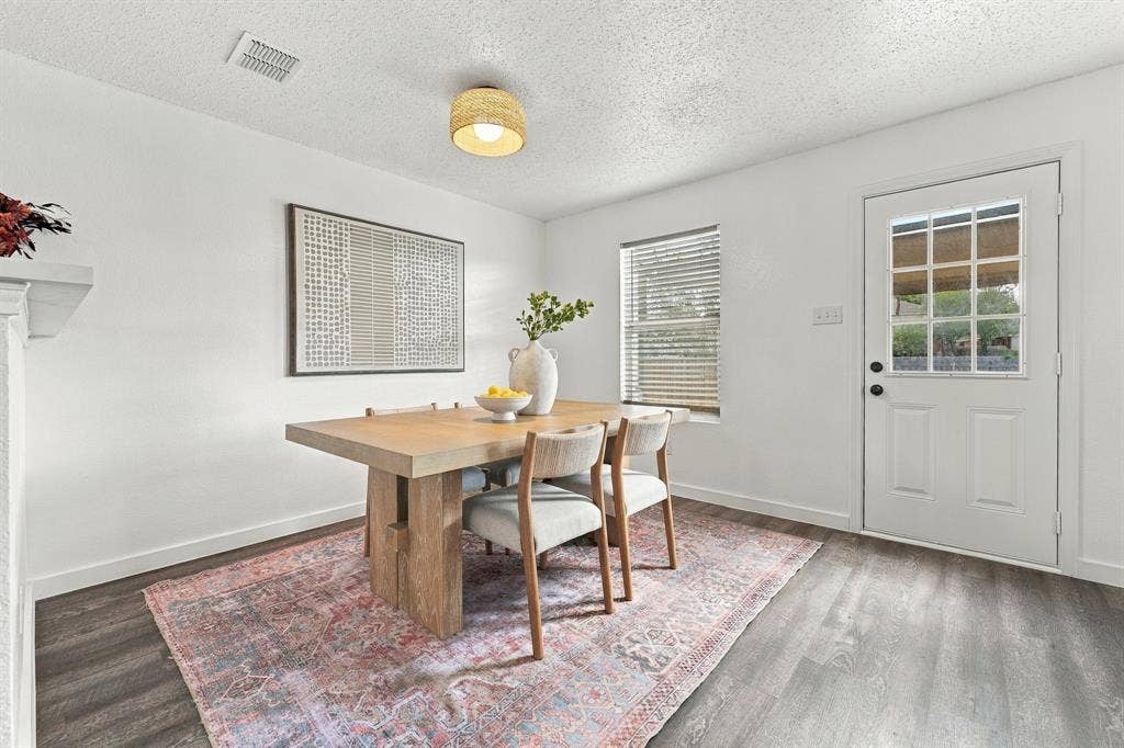 Wood-finish flooring, textured ceiling, cylindrical woven-shade flush mount lighting, single-pane window with horizontal blinds, and a white six-lite exterior door