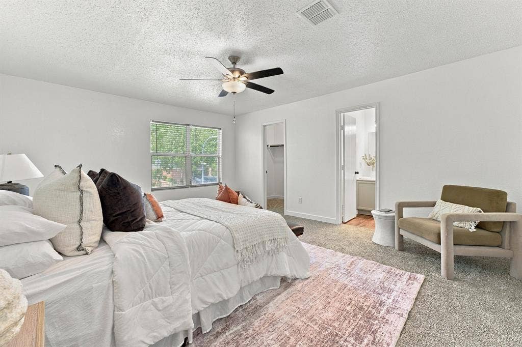Bedroom featuring neutral carpeting, a multi-blade ceiling fan with integrated lighting, and a walk-in closet