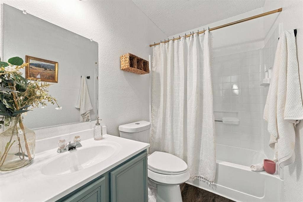 Bathroom featuring a vanity with a white countertop and integrated sink, frameless wall-mounted mirror, and a tub-shower combination with white tile surround