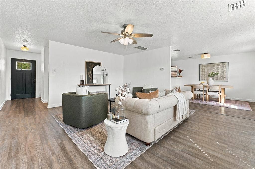 Living area featuring wood-finish flooring, a ceiling fan with integrated lighting, and a black front door with a glass inlay