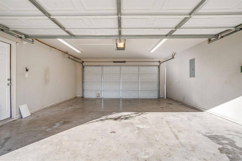 Multi-car garage featuring a sectional overhead door, finished walls, and linear fluorescent lighting