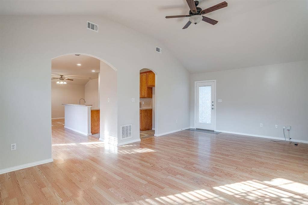 Vaulted ceilings, wood-finish flooring, architectural arched doorways, and a ceiling fan
