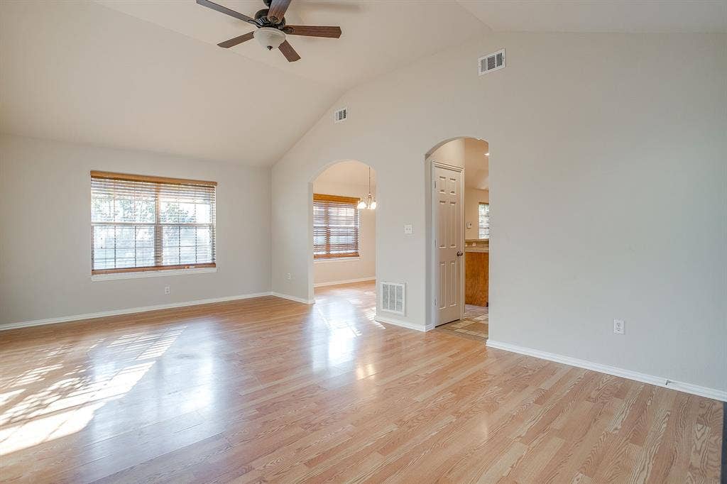 Vaulted ceilings, wood-finish flooring, arched doorways, and a ceiling fan