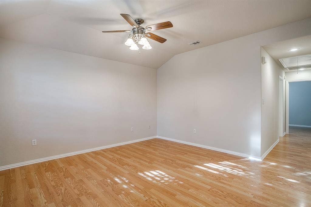 Vaulted ceilings, wood-finish flooring, and a multi-light ceiling fan