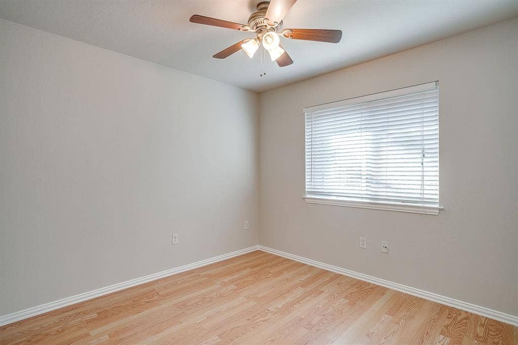 Interior room featuring wood-finish flooring, neutral wall paint, and a ceiling-mounted light fixture with a fan