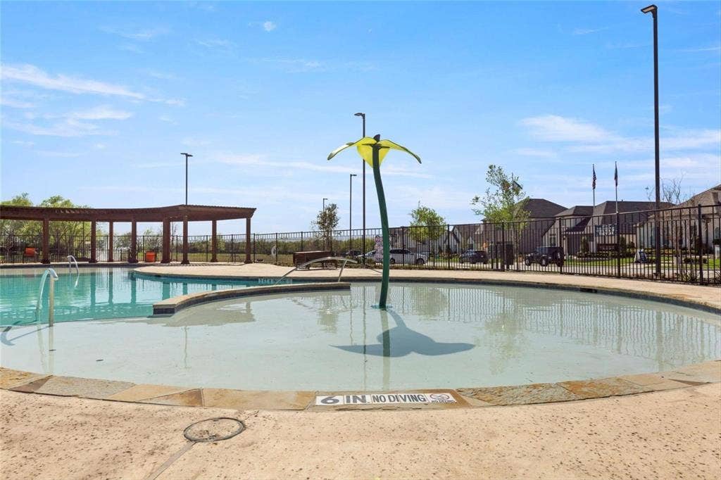 2808 Spring Side Drive, Royse City, TX 75189 Swimming pool featuring a shallow-depth entry area, a central water feature, stone coping, and a detached wooden pergola