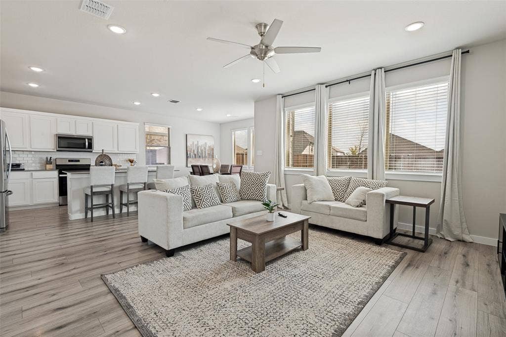 2808 Spring Side Drive, Royse City, TX 75189 Open-concept main room featuring wood-finish flooring, recessed lighting, a brushed-nickel ceiling fan, and large windows with horizontal blinds
