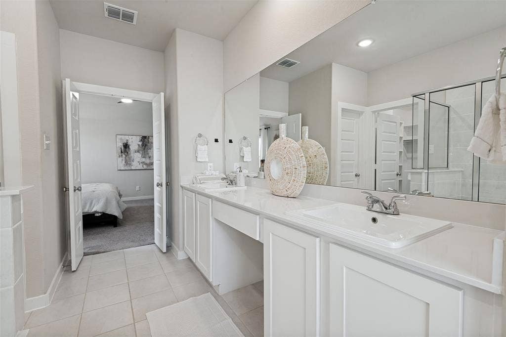 2808 Spring Side Drive, Royse City, TX 75189 Double vanity featuring white cabinetry, a solid-surface countertop, dual drop-in sinks, and a full-width wall mirror