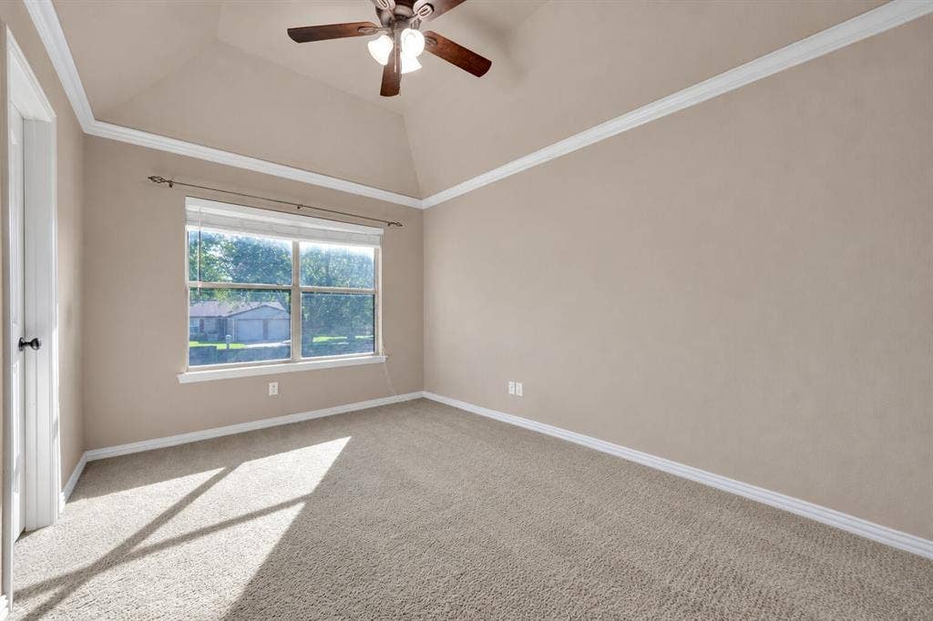 Tray ceiling featuring crown molding, neutral carpeting, and a multi-blade ceiling fan