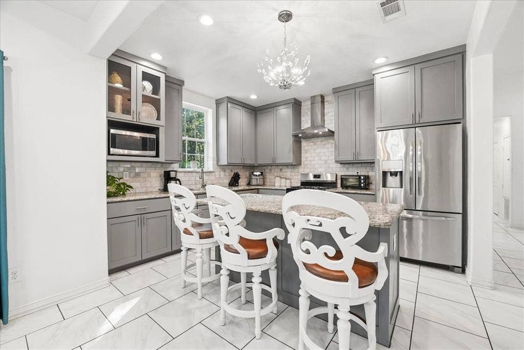 7320 County Road 3512, Quinlan, TX 75474 Kitchen featuring grey shaker-style cabinetry, stone-surface countertops, subway tile backsplash, stainless steel appliances, and tile flooring