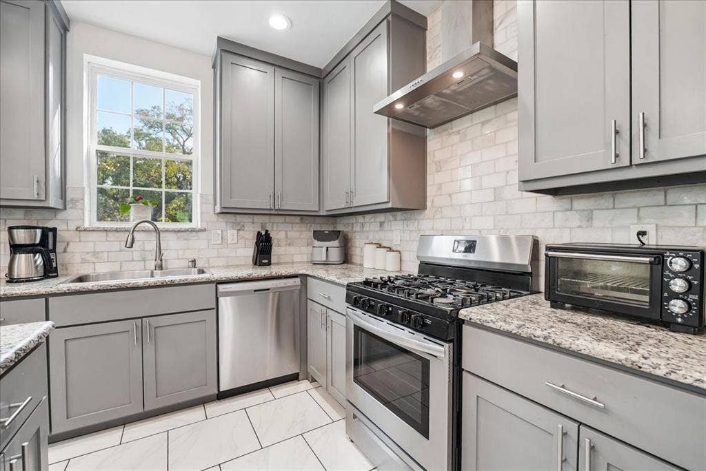7320 County Road 3512, Quinlan, TX 75474 Kitchen featuring grey shaker-style cabinetry, stainless steel appliances, stone-look countertops, a subway tile backsplash, and large-format floor tiles