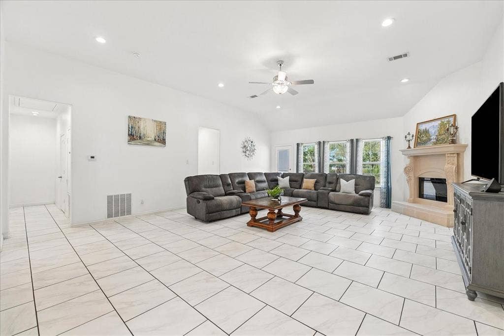 7320 County Road 3512, Quinlan, TX 75474 Living area featuring vaulted ceilings, neutral ceramic tile flooring, recessed lighting, and a decorative fireplace with a stone-finish surround