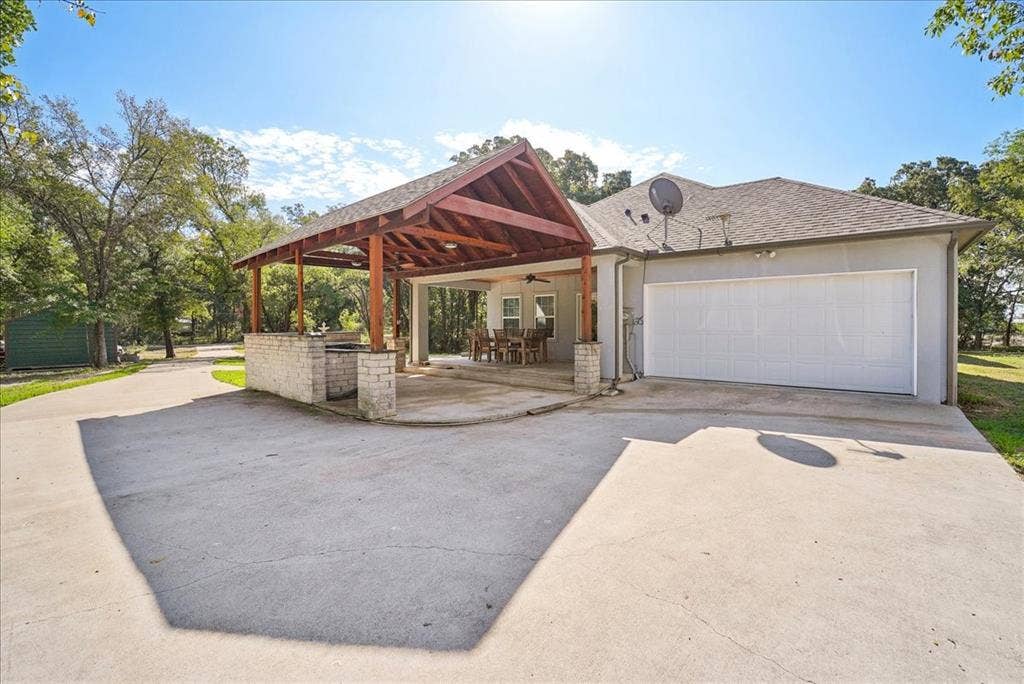 7320 County Road 3512, Quinlan, TX 75474 Covered outdoor pavilion featuring a stone-base prep area, wood-beam vaulted ceiling, integrated ceiling fan, and concrete patio