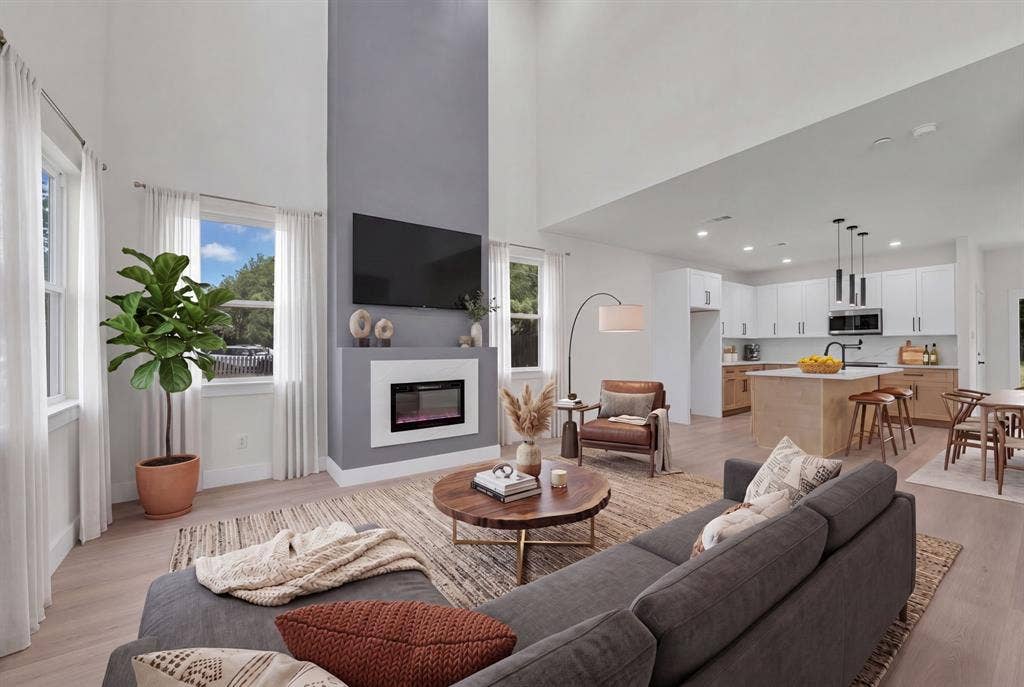 3639 Pueblo Street, Dallas, TX 75212 Double-height ceilings, floor-to-ceiling fireplace feature wall with integrated hearth, wood-finish flooring, kitchen island with built-in cabinetry, and pendant lighting