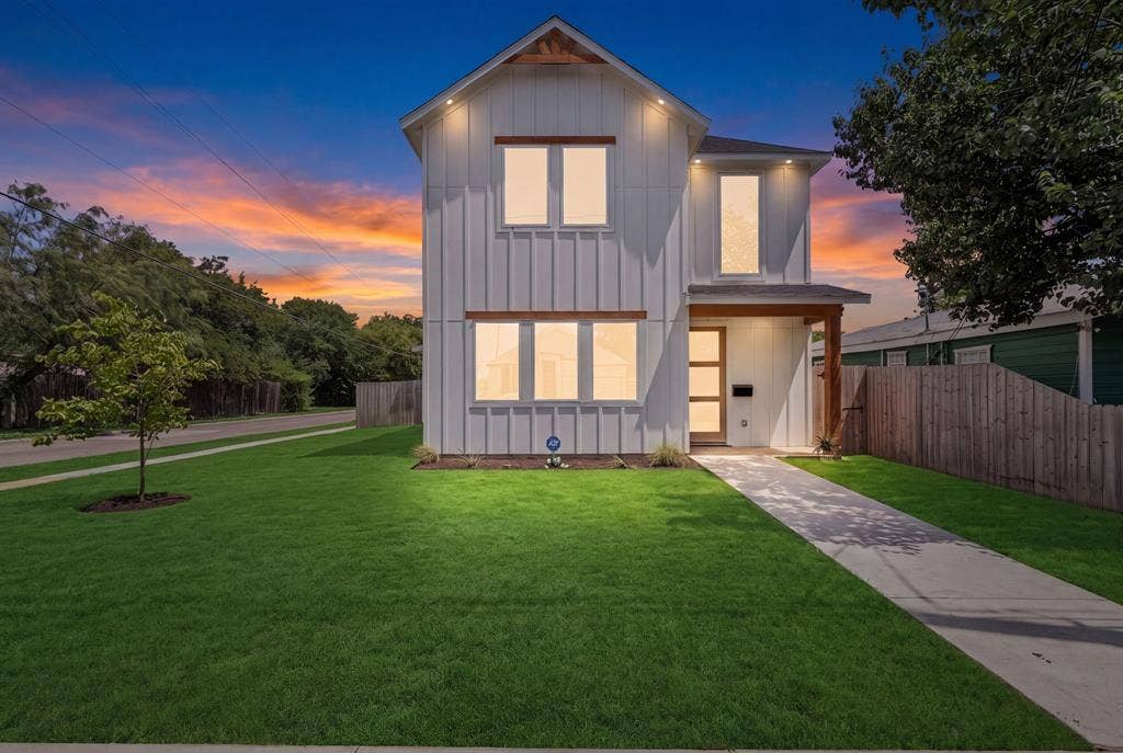3639 Pueblo Street, Dallas, TX 75212 Modern farmhouse exterior featuring vertical board-and-batten siding, natural wood-finish accents, large multi-pane windows, recessed soffit lighting, and a concrete walkway