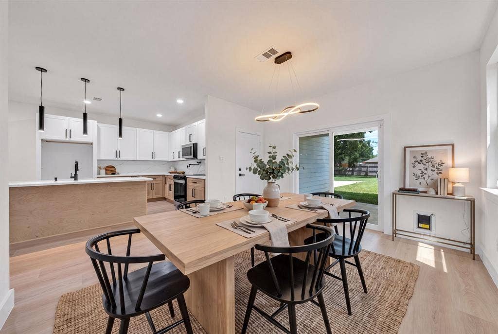 3639 Pueblo Street, Dallas, TX 75212 Kitchen featuring white upper cabinetry, light wood-finish lower cabinetry, stone-look countertops, matte black plumbing fixtures, and wood-finish flooring throughout