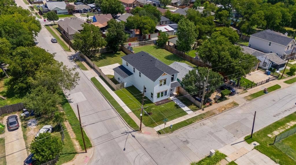 3639 Pueblo Street, Dallas, TX 75212 Corner lot property featuring a white vertical-siding exterior, dark shingled roof, concrete driveway, and expansive grass lawn