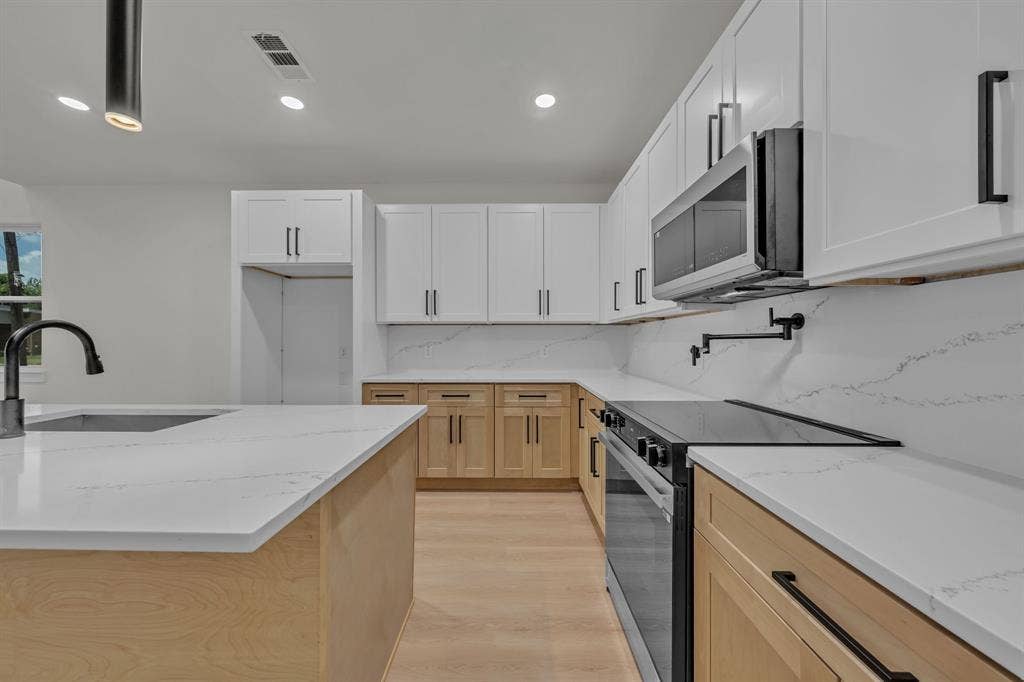 3639 Pueblo Street, Dallas, TX 75212 Kitchen featuring white upper cabinetry, natural wood-finish lower cabinetry, stone-surface countertops, a matching stone-surface backsplash, and a built-in pot filler faucet
