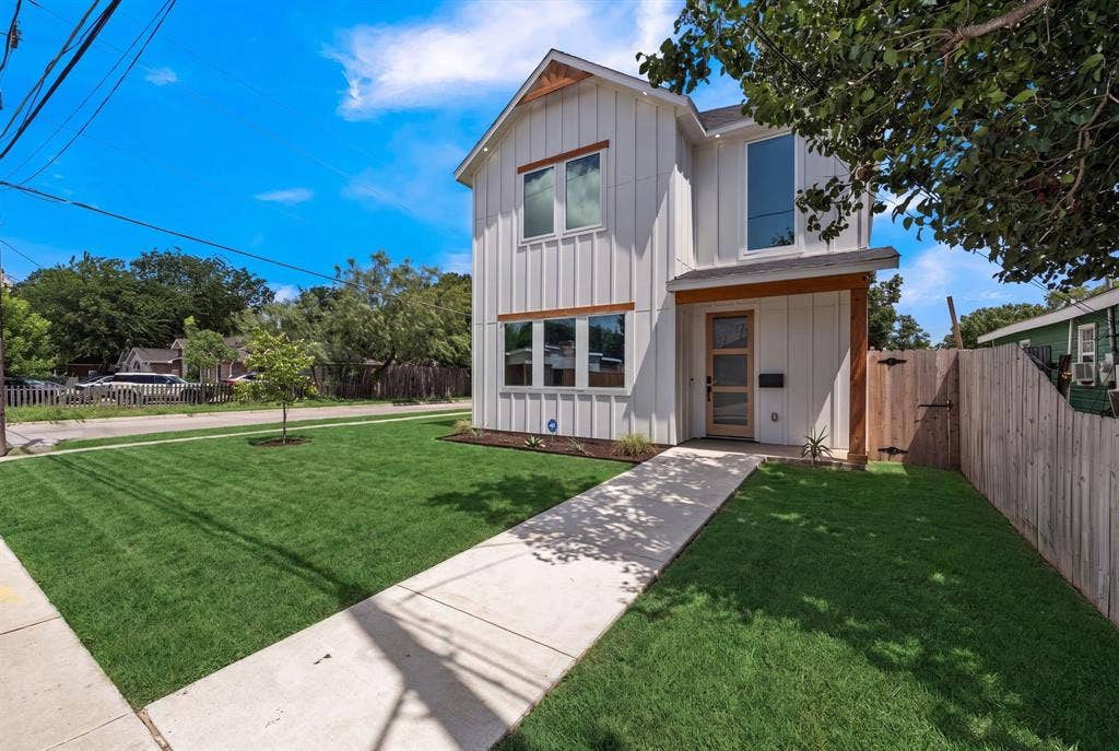 3639 Pueblo Street, Dallas, TX 75212 Two-story vertical siding exterior with wood-tone trim, expansive front lawn, paved walkway, and modern entry door with glass paneling