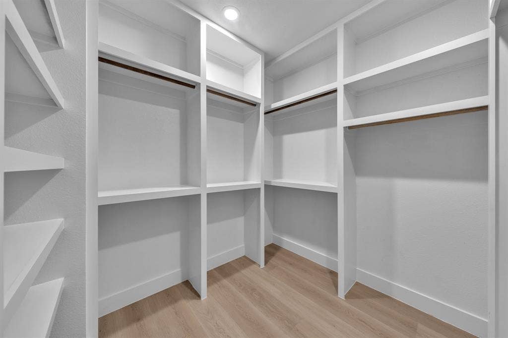 3639 Pueblo Street, Dallas, TX 75212 Custom walk-in closet featuring extensive built-in white shelving, integrated hanging rods, and wood-finish flooring