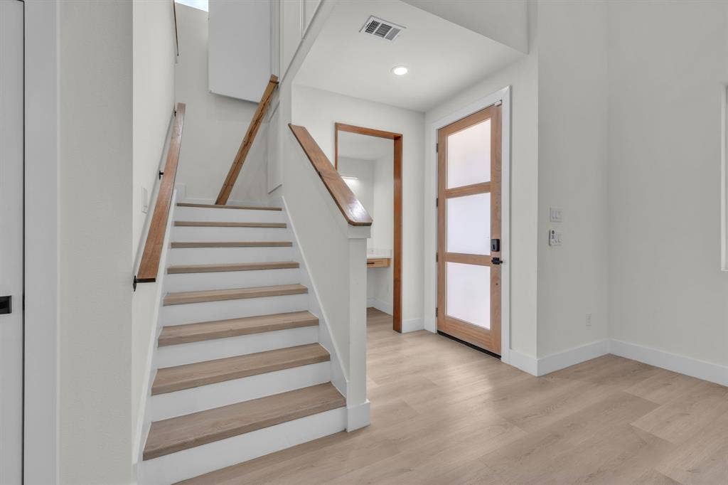 3639 Pueblo Street, Dallas, TX 75212 Entryway featuring a front door with glass panels, wood-finish flooring, and a staircase with wood handrails and wood-tread stairs